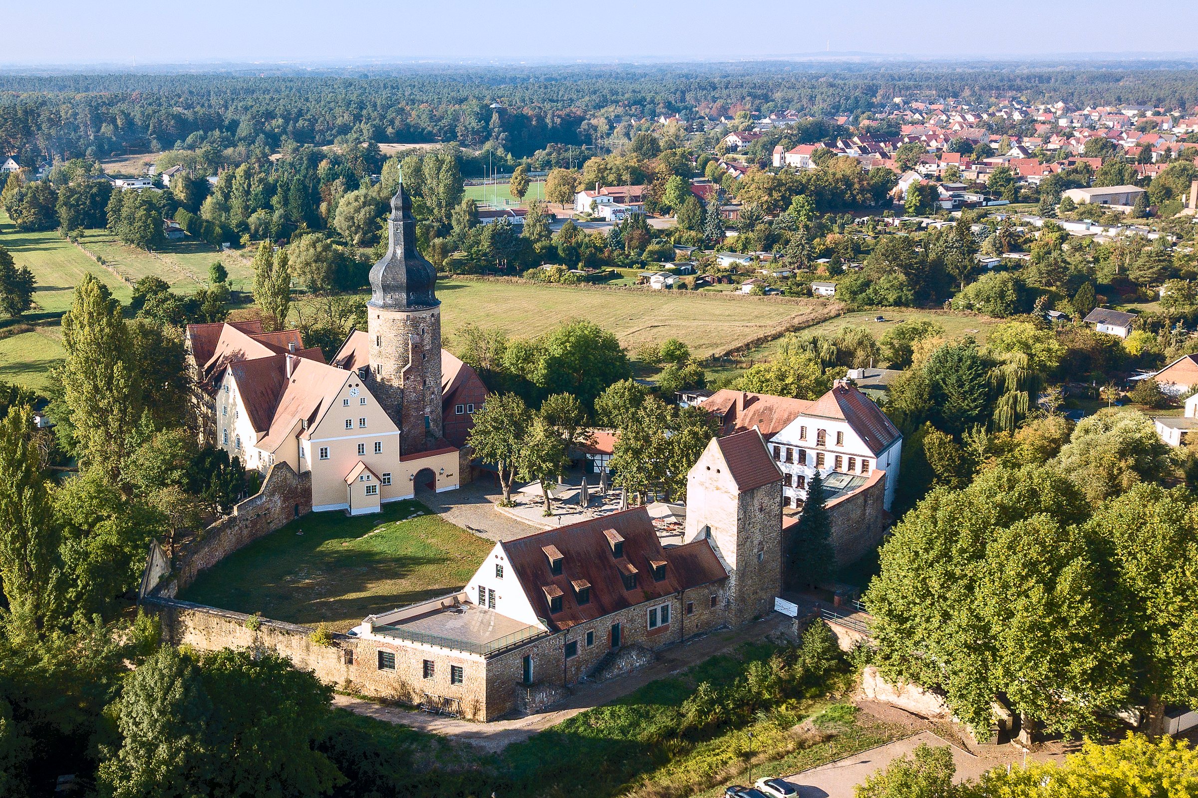 Luftaufnahme der Wasserburg Gommern mit Ringmauer und dem Ort im Hintergrund