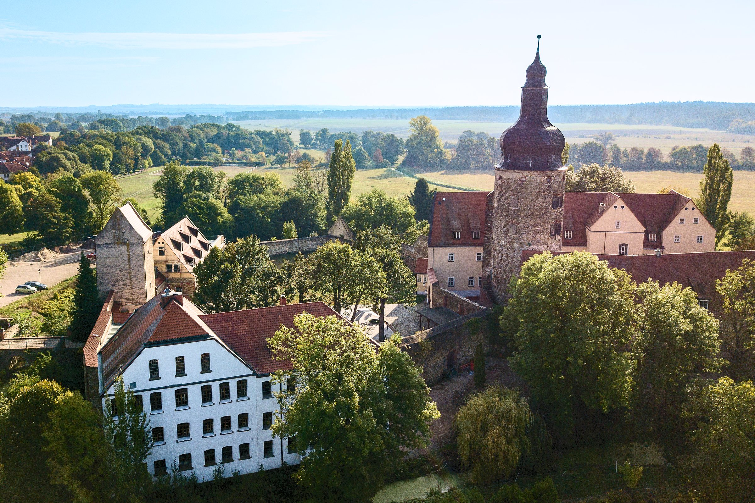 Wasserburg Gommern aus der Luft mit Bergfried, weißem Gebäude und weiter Landschaft